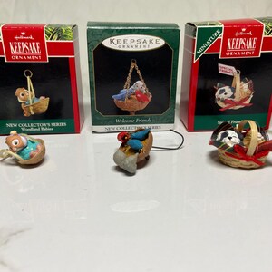 May include: Three Hallmark Keepsake miniature Christmas ornaments. The first ornament features a squirrel in a basket. The second ornament features a bird in a basket. The third ornament features a dog in a basket.