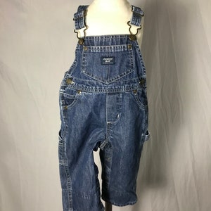May include: Blue denim overalls with adjustable straps and a Champion brand label. The overalls have multiple pockets and a button closure.