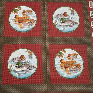 May include: Fabric panel featuring four circular duck illustrations set against a red and green background. Each circle depicts ducks swimming in water, surrounded by foliage. The border includes oval duck images.