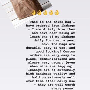May include: A brown canvas crossbody bag with a dark blue adjustable shoulder strap, featuring a front pocket with a silver metal snap button closure and visible stitching details across the exterior surface of the bag.