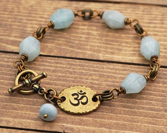 Light blue om bracelet, aquamarine semiprecious stone beads, brass tones, fits 6 1/4 inch wrist, 8 inches long