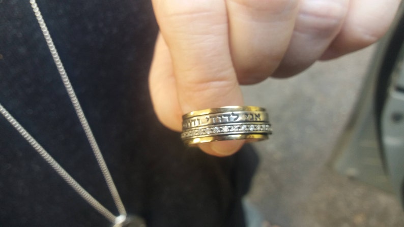 K&ouml;nnte beinhalten: Ein goldener Ring mit einer Band aus hebr&auml;ischem Text und einer Reihe kleiner Diamanten.