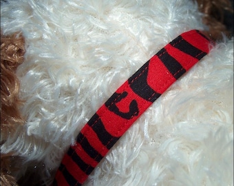 Könnte beinhalten: Ein rot-schwarzes gestreiftes Hundehalsband mit einem genähten Design.