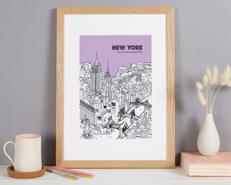 May include: Framed black and white illustration of the New York City skyline, with a lavender background and the text "NEW YORK" and "Our Honeymoon April 2016". The artwork is in a light wood frame.