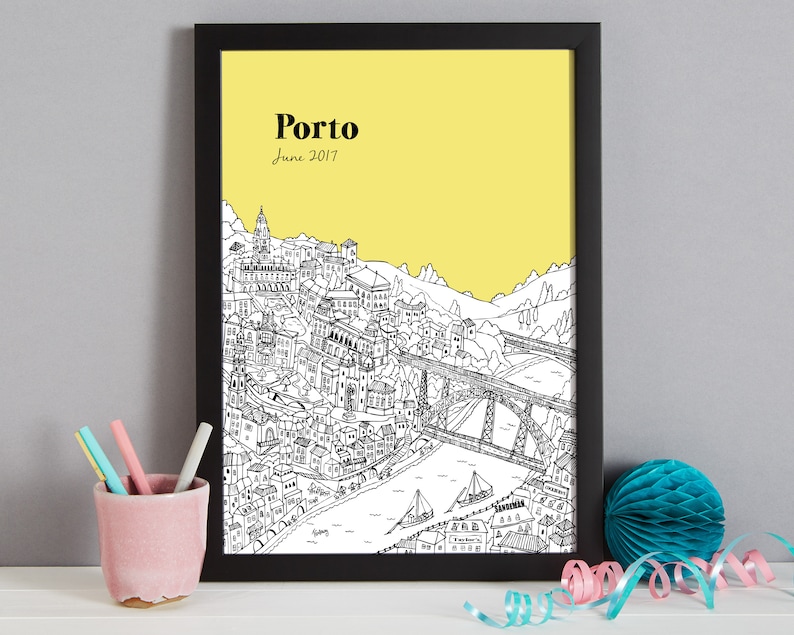 May include: Black framed print featuring a detailed black and white illustration of Porto, Portugal, set against a yellow background. The word "Porto" and the date "June 2017" are printed at the top. The artwork depicts buildings, bridges, and boats.