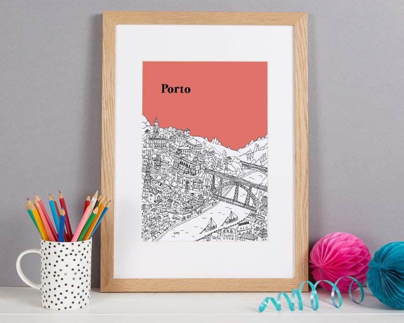 May include: Framed art print featuring a detailed black and white illustration of Porto, Portugal, with a salmon-colored sky and the city's name in black. The print is in a light wood frame.