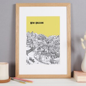 May include: A framed black and white line drawing of the New Orleans skyline with a yellow background. The drawing includes buildings, a bridge, and a river.