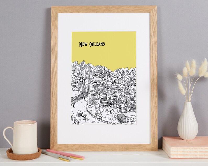 May include: A framed black and white line drawing of the New Orleans skyline with a yellow background. The drawing includes buildings, a bridge, and a river.