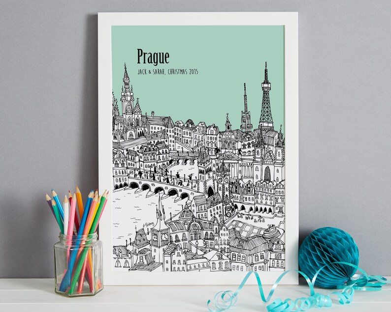 Op de afbeelding: Een zwart-witte lijntekening van de skyline van Praag met de tekst "Praag" en "Jack & Sarah, Kerstmis 2015" op een lichtblauwe achtergrond.