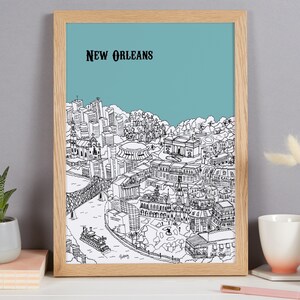 May include: A framed black and white line drawing of the New Orleans skyline against a light blue background. The drawing includes iconic buildings and landmarks, such as the French Quarter, the Superdome, and the Mississippi River.