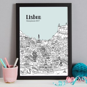 May include: A black and white line drawing of the city of Lisbon, Portugal. The drawing includes the iconic landmarks of the city, such as the Castelo de S&atilde;o Jorge and the Jer&oacute;nimos Monastery. The text "Lisbon Honeymoon 2017" is printed at the top of the drawing.