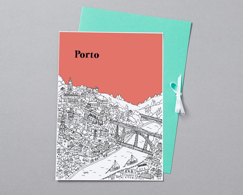 May include: A greeting card featuring a black and white illustration of Porto, Portugal, with the city's name in black text against a coral background. The card is paired with a teal envelope tied with a white ribbon.