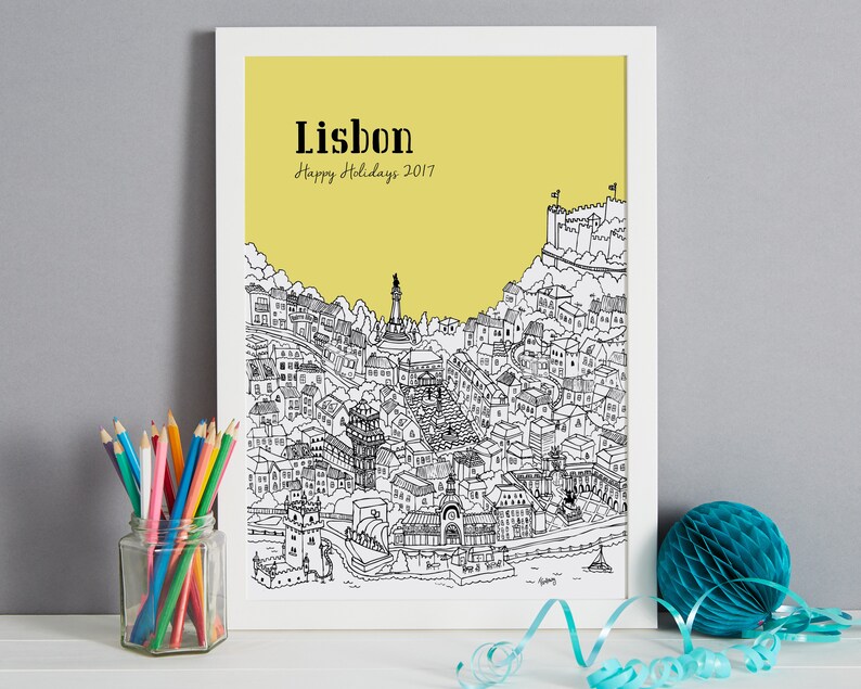 May include: A black and white line drawing of the city of Lisbon, Portugal, on a yellow background. The drawing includes buildings, streets, and landmarks. The text "Lisbon" and "Happy Holidays 2017" is printed in black at the top of the image.