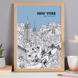 May include: A framed black and white illustration of New York City with a light blue sky background. The artwork includes iconic landmarks like the Empire State Building, Chrysler Building, and the Statue of Liberty. Text at the top reads "NEW YORK Happy Memories 2017".