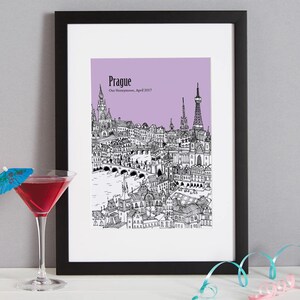 Op de afbeelding: Een zwart-witte illustratie van de skyline van Praag op een lichtpaarse achtergrond. De tekst "Praag" en "Onze huwelijksreis, april 2017" staat onder de illustratie.