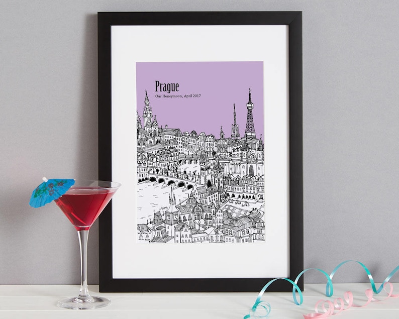 Op de afbeelding: Een zwart-witte illustratie van de skyline van Praag op een lichtpaarse achtergrond. De tekst "Praag" en "Onze huwelijksreis, april 2017" staat onder de illustratie.