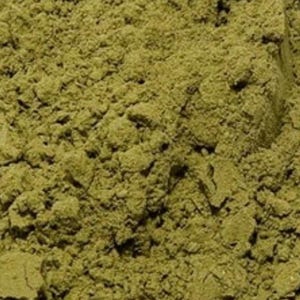 Puede incluir: Primer plano de un montón de polvo finamente molido, de color verde oliva. La textura es granular e irregular, con pequeños grumos y variaciones de tono. La apariencia general sugiere una sustancia natural y terrosa.