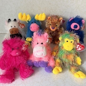 May include: A collection of colorful plush animal toys, including a cow, moose, bear, horse, and monkey. The toys feature various colors like pink, blue, green, and brown, with attached tags.