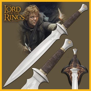 May include: A silver sword with a brown leather handle and a gold-colored pommel. The sword is displayed on a black and gold wall mount with a decorative design. The sword is from the Lord of the Rings movie franchise.