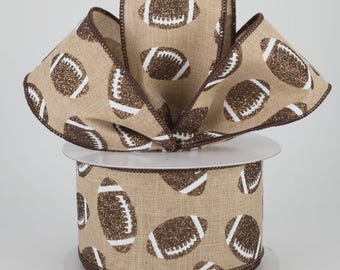 May include: A roll of decorative ribbon featuring a repeating pattern of brown glitter footballs with white details on a tan background. The ribbon has a brown stitched edge and is ideal for crafting and decorating.