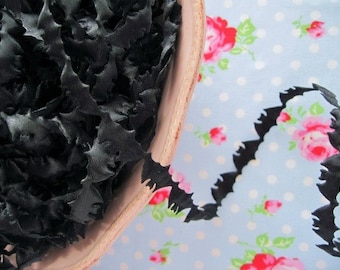 May include: A bowl filled with black felt bat cutouts. The bowl is sitting on a blue and white fabric with a floral pattern.