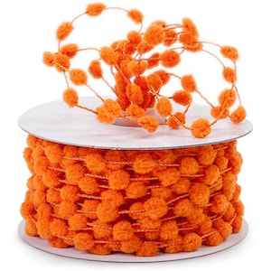May include: A spool of orange pom-pom trim. The trim is made of small, round, fuzzy pom-poms attached to a thin cord. The spool is white and the trim is a bright, solid orange color. The trim is suitable for crafts and decorations.