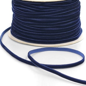 May include: A spool of dark blue velvet ribbon. The ribbon is wound around a cardboard spool and is ready to be used for crafting or decorating.