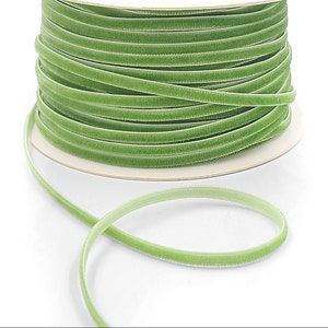 May include: A spool of green velvet ribbon. The ribbon is wound around a white cardboard spool. The ribbon is about 1/4 inch wide.