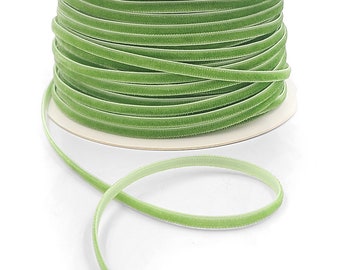 May include: A spool of green velvet ribbon. The ribbon is wound around a white cardboard spool. The ribbon is about 1/4 inch wide.