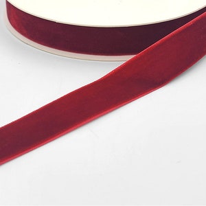 May include: A roll of deep red velvet ribbon. The ribbon is smooth and has a slight sheen.