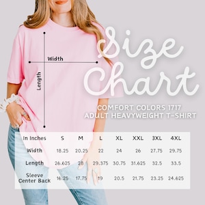 May include: A light pink Comfort Colors adult heavyweight t-shirt with a size chart. The chart lists measurements in inches for width, length, and sleeve center back for sizes S through 4XL. The text "Size Chart" is in a cursive font.