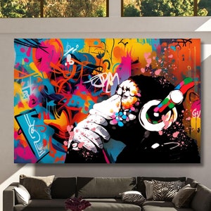 Può includere: Un dipinto astratto colorato di una scimmia con le cuffie. Lo sfondo è un mix di colori vivaci e disegni in stile graffiti.