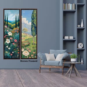 May include: Two vertical wall art pieces in dark brown frames featuring landscape paintings of a lush garden with colorful flowers, tall cypress trees, a wooden bench, and distant mountains under a blue sky with white clouds.