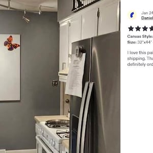 a kitchen with a refrigerator, stove, and a painting of a person reaching for a butterfly on the wall.