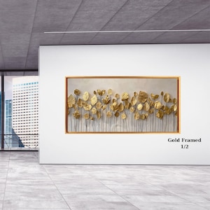 May include: A rectangular wall art piece featuring a collection of metallic gold leaves on thin stems against a light, textured background, all enclosed within a thin gold frame. The text "Gold Framed 1/2" is visible in the bottom right corner.