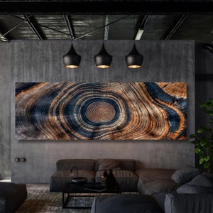 Op de afbeelding: Een groot rechthoekig wandkunstwerk met een hoge resolutie print van een dwarsdoorsnede van een boomstam. De afbeelding toont concentrische groeiringen in tinten diep marineblauw, donker antraciet en warme natuurlijke houtbruine kleuren.