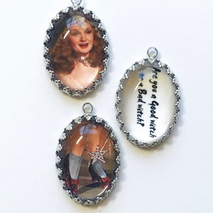 May include: Three oval pendants with silver scalloped edges. One shows a woman with wavy hair, another shows legs in white socks and red shoes holding a star wand, and the third features the black text: Are you a good witch or a Bad witch?