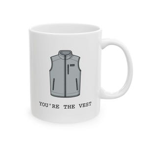 Op de afbeelding: Witte keramische mok met een grijze vestillustratie met een rits en zakken. De tekst "YOU'RE THE VEST" staat onder het vestontwerp. De mok heeft een gebogen handvat.