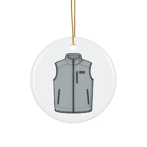 Puede incluir: Adorno navideño redondo y blanco con un diseño de chaleco gris. El chaleco tiene cremallera, bolsillos y un pequeño parche. Se adjunta una cuerda dorada para colgarlo. Artículo decorativo.