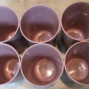 May include: Six matching, cylindrical, mauve-colored planters. The planters have a smooth, glossy finish and a slightly darker interior. The arrangement shows the planters in a circular pattern, perfect for indoor or outdoor use.