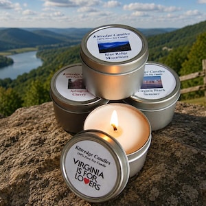 May include: Four round silver metal tins containing soy candles. Labels feature text including Kittredge Candles, 100% Pure Soy Candle, Blue Ridge Mountains, Arlington Cherry, Virginia Beach Summer, and Virginia Is For Lovers with a red heart icon.