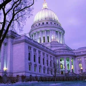 May include: A large, white, domed building with a tall, central tower. The building has many windows and is lit up at night. The building is surrounded by trees and a grassy lawn.