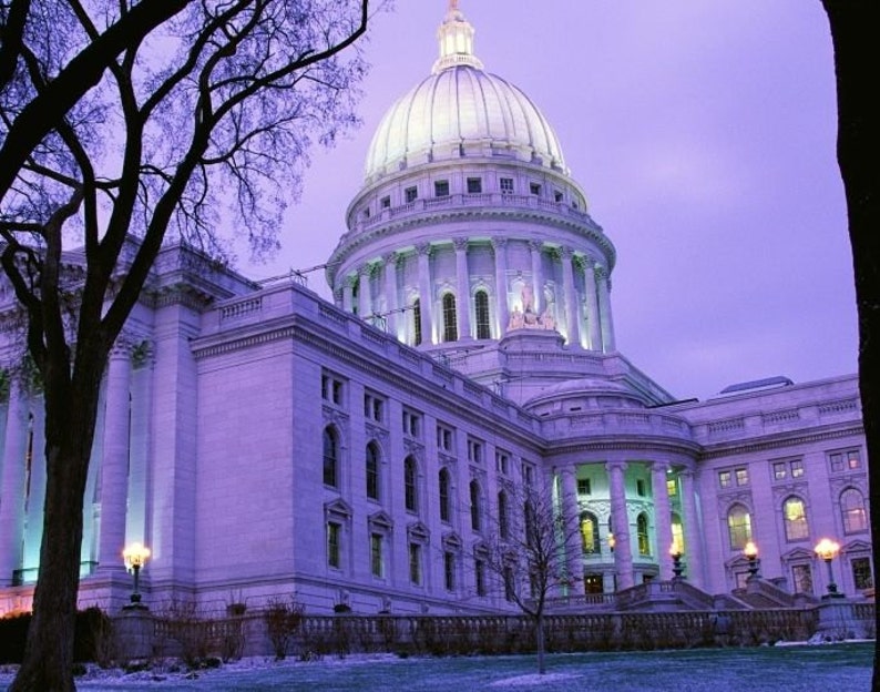 May include: A large, white, domed building with a tall, central tower. The building has many windows and is lit up at night. The building is surrounded by trees and a grassy lawn.