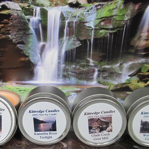May include: Four round silver metal tins containing soy candles, each with a white label featuring the Kittredge Candles logo and specific scene names: Country Roads, Kanawha River Twilight, Glade Creek Grist Mill, and West Virginia Coal Mine.
