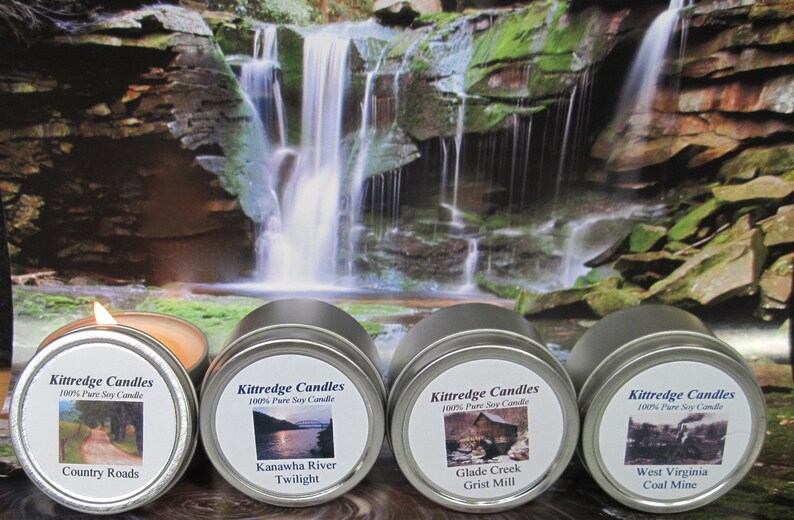 May include: Four round silver metal tins containing soy candles, each with a white label featuring the Kittredge Candles logo and specific scene names: Country Roads, Kanawha River Twilight, Glade Creek Grist Mill, and West Virginia Coal Mine.