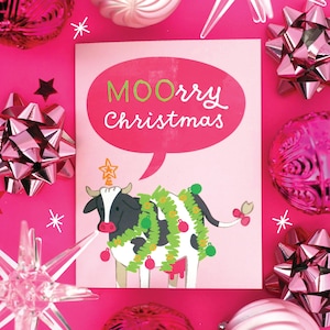 May include: A pink Christmas card with the text "MOOrry Christmas" in a speech bubble. The card features a cartoon cow decorated with Christmas ornaments and a star on its head. Pink bows and ornaments surround the card.