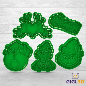 May include: A collection of five green plastic cookie cutters featuring characters and text from "The Grinch." Designs include the Grinch's face, a heart-shaped hand gesture, and the words "The Grinch."