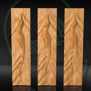 May include: Three wooden panels with carved alligator designs. The alligators are depicted in a vertical orientation, with detailed scales and a curved body. The wood has a natural, light brown color.