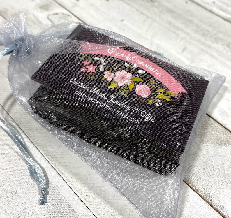 May include: A small, black gift bag with a floral design and the text "Qberry Creations Custom Made Jewelry & Gifts qberrycreations.etsy.com" is inside a light blue organza bag.