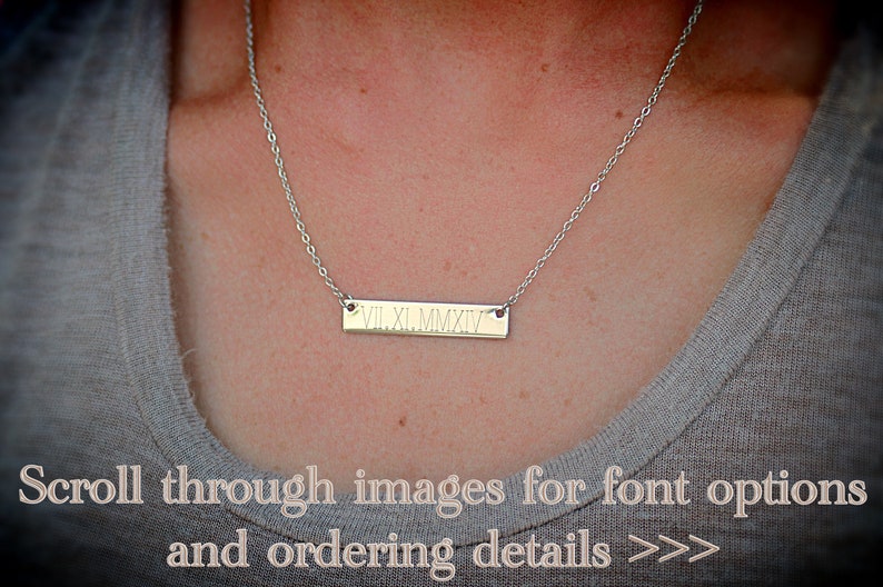 May include: A silver necklace with a bar pendant engraved with the Roman numerals VII.XI.MMXIV.